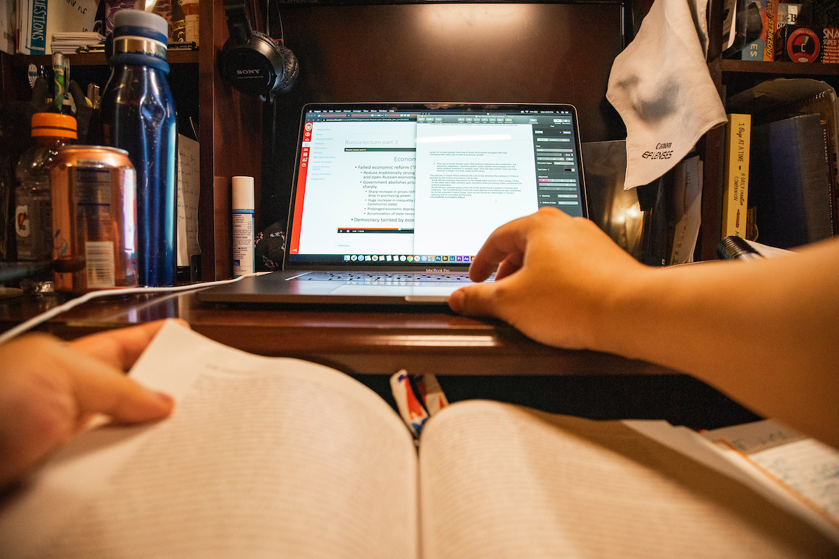 A student working from a textbook and a computer screen.