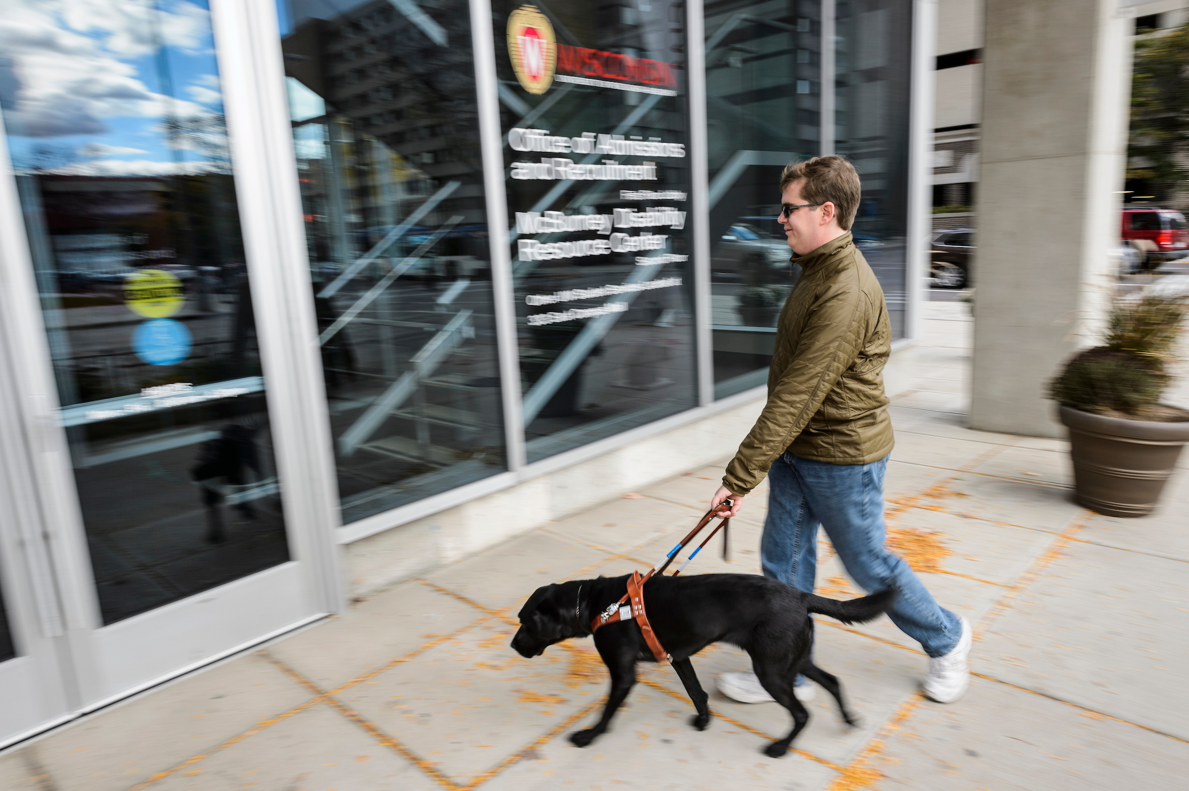 A person and their service dog walk into the McBurney building.